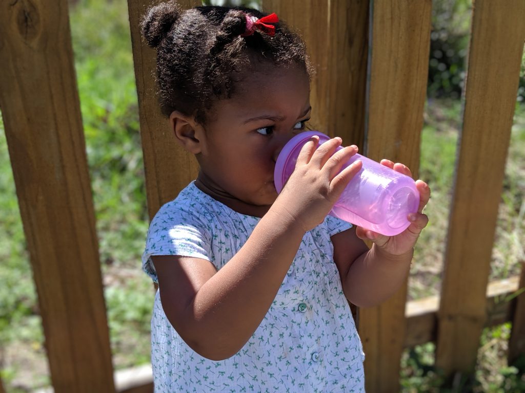 Solilyanna With Purple Bottle Drinking Looking To Left With Fence Behind